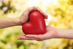Red,Heart,In,Woman,And,Man,Hands,,On,Green,Background